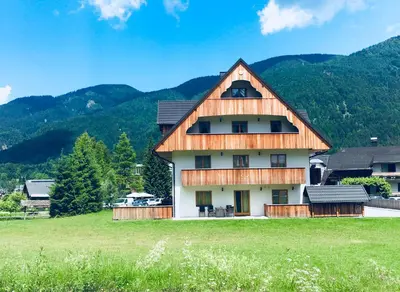 a house in a field with mountains in the background at Vall’s apartment- by ski slopes in Kranjska Gora