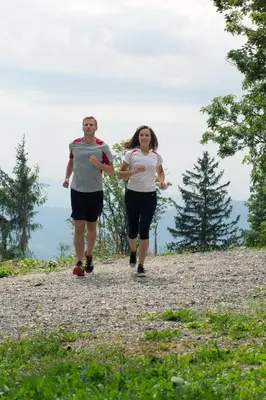 a man and woman running on a hill with a frisbee at ETNO HOUSE GOSTECE- Suite with Finnish sauna in Mozirje