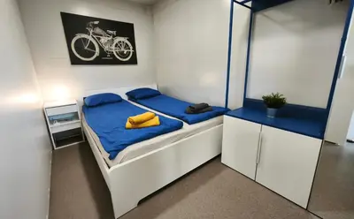 a bedroom with a bed with blue sheets and a bike on the wall at Rooms & Apartments Jana in Cerklje na Gorenjskem