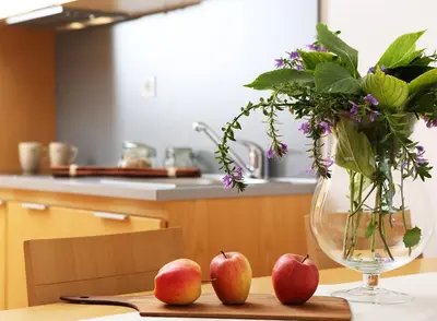 a vase with flowers and three apples on a table at Apartments and Rooms Bernik in Kranjska Gora