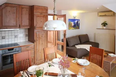 a kitchen and living room with a table and a couch at Apartments and Rooms Bernik in Kranjska Gora