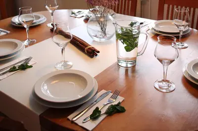 a wooden table with plates and wine glasses on it at Apartments and Rooms Bernik in Kranjska Gora
