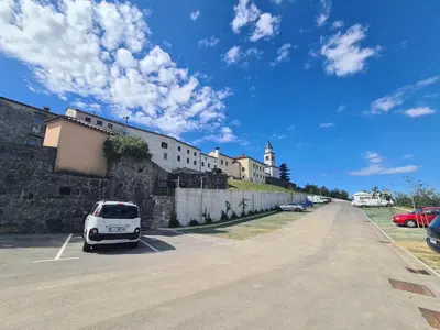 a white car parked in a parking lot next to a building at Apartma in soba Vipavski Križ in Ajdovščina