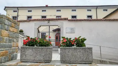 a building with two planters with flowers in front of it at Apartma in soba Vipavski Križ in Ajdovščina