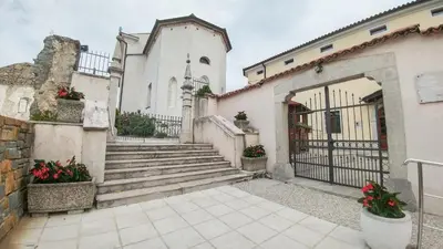 a white building with stairs and a gate with flowers at Apartma in soba Vipavski Križ in Ajdovščina