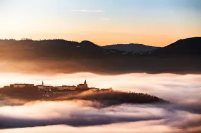 a view of a city above the clouds at sunset at Apartma in soba Vipavski Križ in Ajdovščina