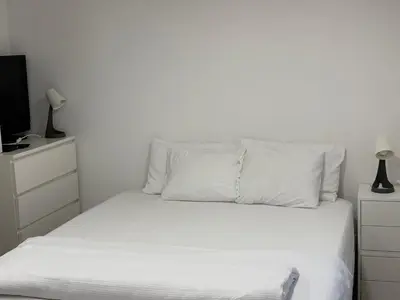 a bedroom with a bed with white sheets and a tv at Industrial Studio 6 in Ljubljana