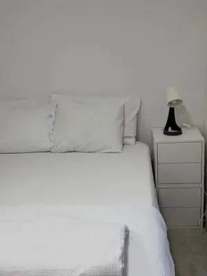 a white bed with a lamp on a night stand at Industrial Studio 6 in Ljubljana