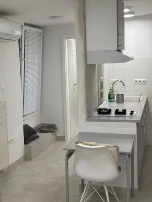 a white kitchen with a white chair and a sink at Industrial Studio 6 in Ljubljana