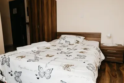 a bed with a white comforter with butterflies on it at Apartments-rooms Vogrinec in Ptuj