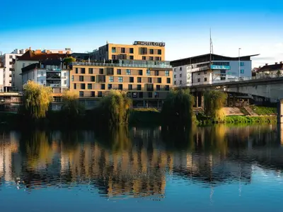 a building next to a body of water at Hotel City Maribor in Maribor