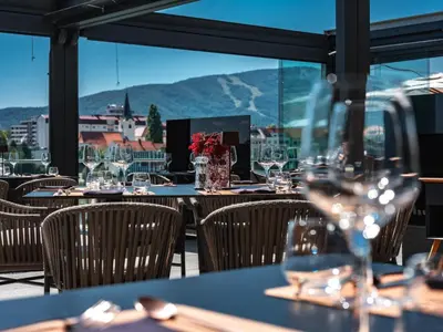 a restaurant with tables and chairs with wine glasses at Hotel City Maribor in Maribor