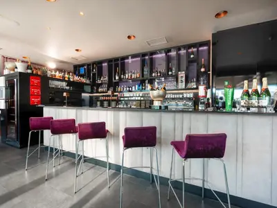 a bar with purple bar stools in a room at Hotel City Maribor in Maribor