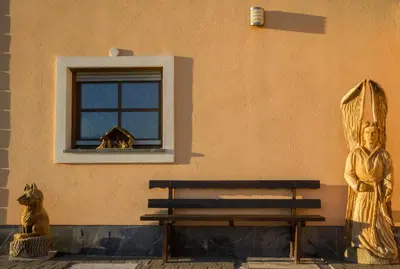 a bench next to a wall with a window and a statue at Vila Silva Marija Apartments in Pišece