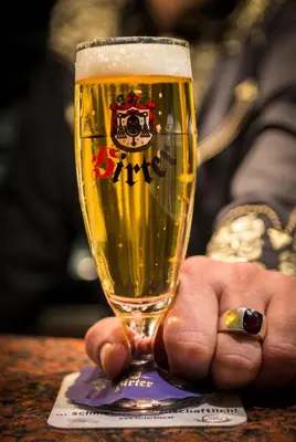 a hand holding a glass of beer on a table at Hotel Krona Domžale in Domžale