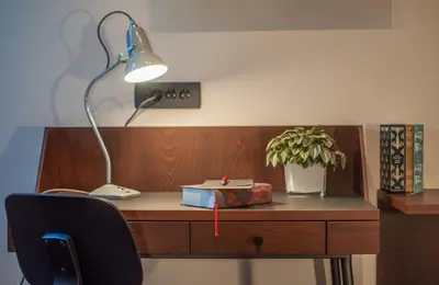 a desk with a lamp and a book and a plant at Hotel Mrak in Ljubljana