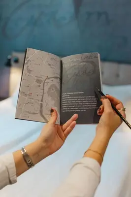 two hands holding a book and a person holding a pair of scissors at Hotel Mrak in Ljubljana