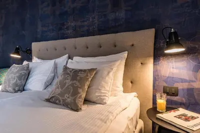 a bedroom with a bed with white pillows and a table at Hotel Mrak in Ljubljana