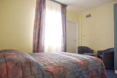 a bedroom with a bed and a window and chairs at Garni Hotel Siesta in Nova Gorica