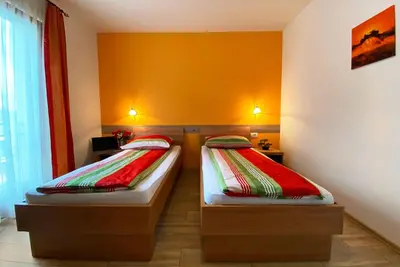 two twin beds in a room with orange walls at Guesthouse Mesec Zaplana in Vrhnika