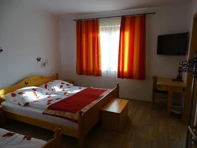 a bedroom with a bed and a window with orange curtains at Guesthouse Mesec Zaplana in Vrhnika