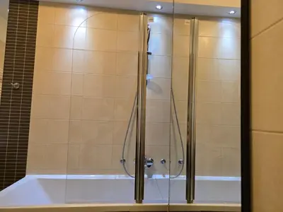 a shower with a glass door next to a tub at Sun and Spa Apartment in Kranjska Gora