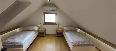 two beds in a attic room with a window at Green Garden Apartment in Bled