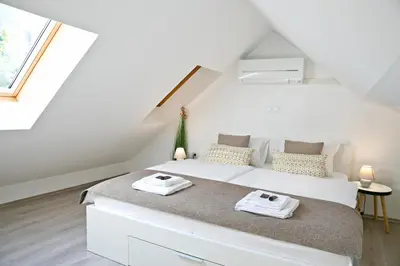 a bedroom with a large white bed in a attic at Apartments Hiša Pod Gradom in Ljubljana