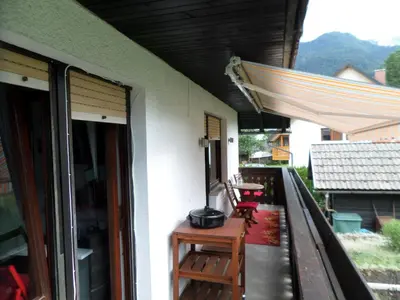 a balcony with a table and a grill on a house at Snežak (Snowman) in Bohinj