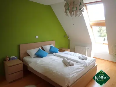 a bedroom with a bed with white sheets and blue pillows at Wild Soca House Apartment No.5 in Bovec