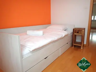 a white bed with an orange wall at Wild Soca House Apartment No.5 in Bovec