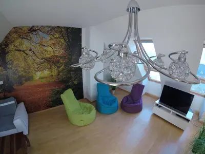a living room with a chandelier and some colorful chairs at Wild Soca House Apartment No.5 in Bovec