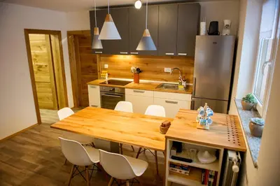 a kitchen with a wooden table and white chairs at Apartments Laznica in Cerkno