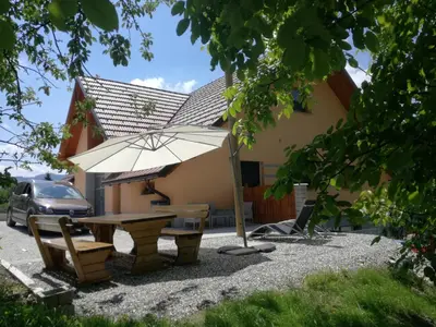 a table and an umbrella in front of a house at Apartments Laznica in Cerkno