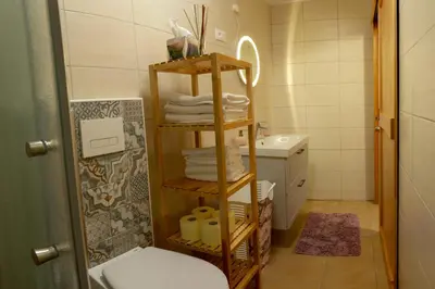 a bathroom with a shelf with towels and a sink at Apartments Laznica in Cerkno