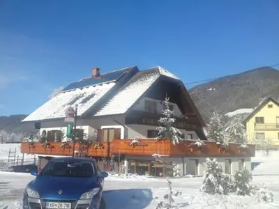 a blue car parked in front of a large house at gostišče uh- planica in Rateče