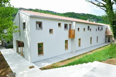 a white building with windows on the side of it at Youth Hostel Ajdovscina in Ajdovščina