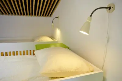 a bedroom with a bed with a lamp and a pillow at Youth Hostel Ajdovscina in Ajdovščina