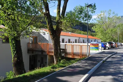 a building with cars parked in a parking lot at Youth Hostel Ajdovscina in Ajdovščina