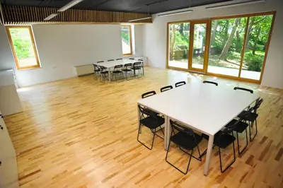 a room with tables and chairs in a room with wood floors at Youth Hostel Ajdovscina in Ajdovščina