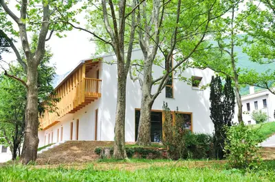 a white house with trees in front of it at Youth Hostel Ajdovscina in Ajdovščina
