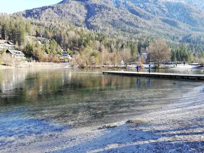 a body of water with a dock and a mountain at Apartma Viktorija in Kranjska Gora