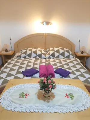 a bed with purple pillows and a vase with flowers on it at Apartment Sonce in Bohinj