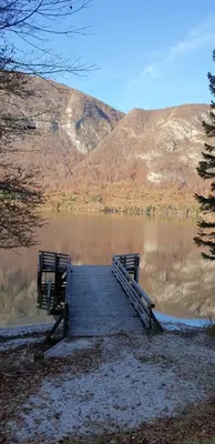 a wooden bridge over a lake with a mountain at Apartment Sonce in Bohinj