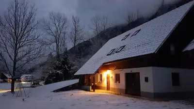 a house with a snow covered roof with lights on it at Apartment Sonce in Bohinj