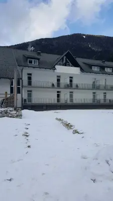 a large white building with snow in front of it at Apartma Kurji vrh - Chicken top in Kranjska Gora
