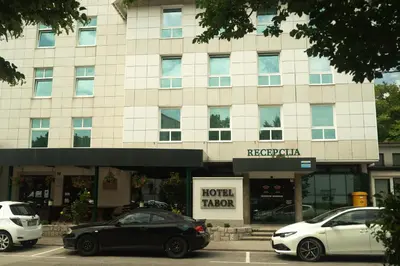 two cars parked in front of a building at Hotel Tabor in Sežana