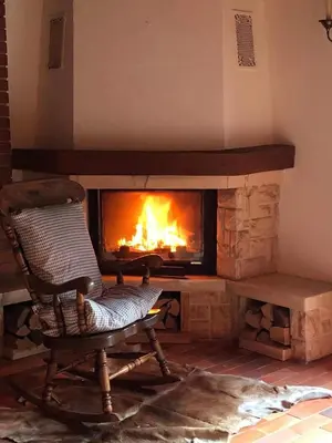 a rocking chair in front of a fireplace at MaxDan Lodge in Kranjska Gora