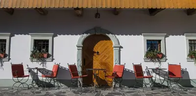 a group of chairs sitting outside of a building with a door at Penzion Mayer in Bled