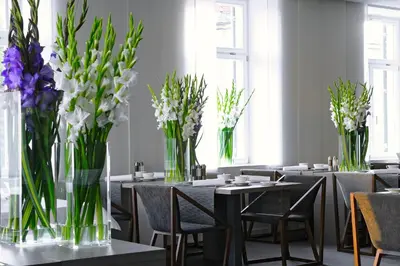 a dining room with tables with vases of flowers at Hotel Cubo in Ljubljana